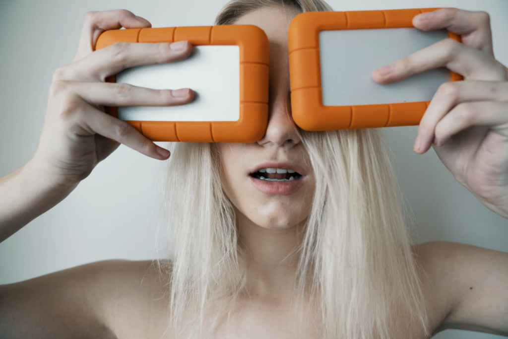 Woman holding up a pair of external hard drives.