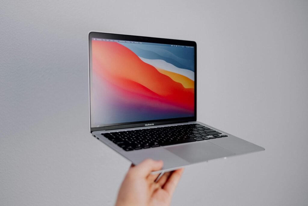A hand holding up a MacBook Air