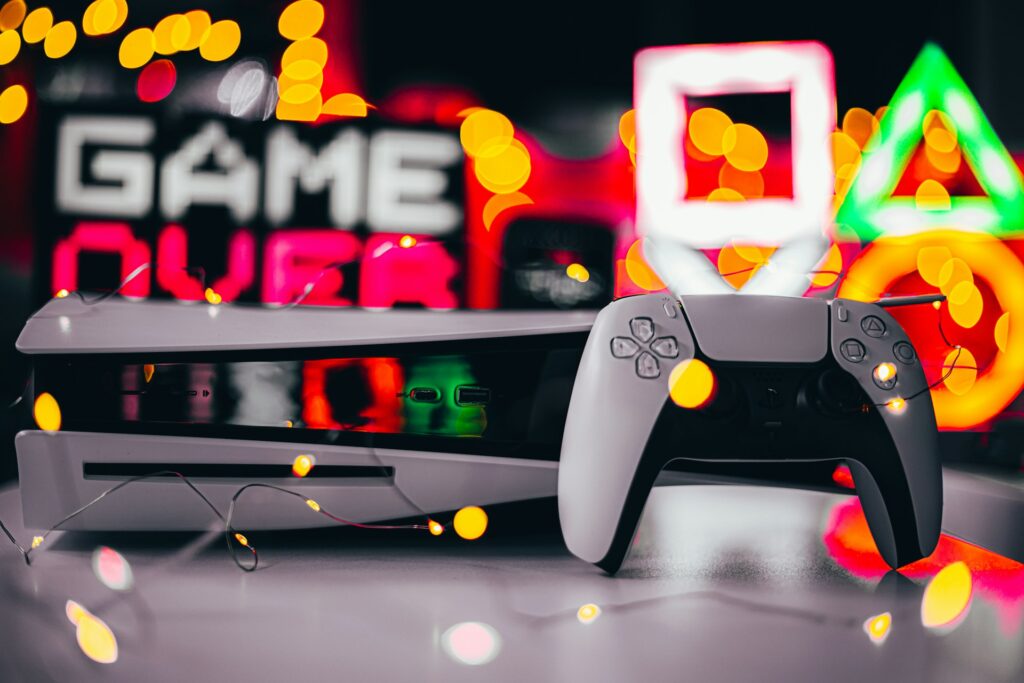A PS5 console and controller in front of a sign that says Game Over